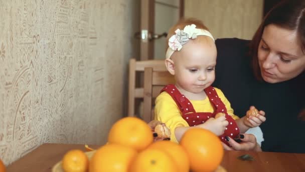 Barn med sin mamma äter tangerin — Stockvideo