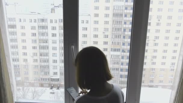 Menina bonita usando um smartphone na frente da janela — Vídeo de Stock