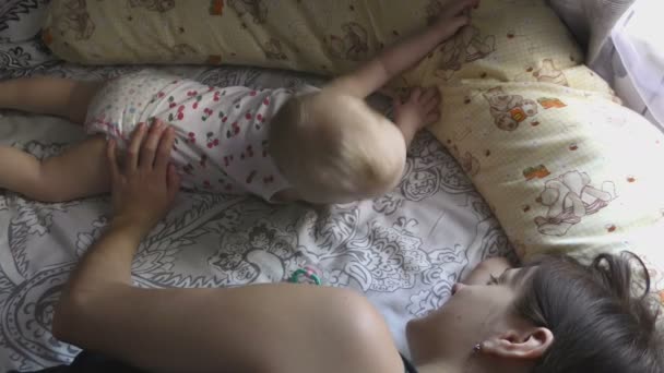 Meisje van de baby met haar moeder tot op bed — Stockvideo