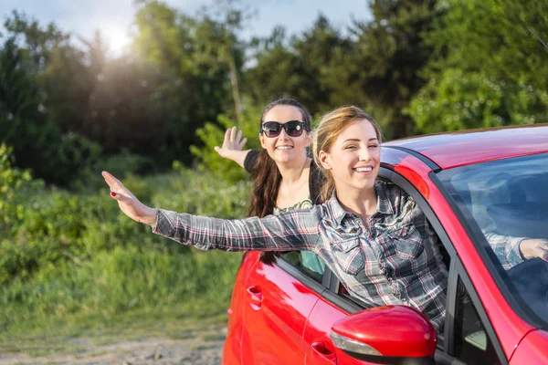 Κορίτσια σε ένα κόκκινο αυτοκίνητο στο ηλιοβασίλεμα. Έννοια του ταξιδιού. — Φωτογραφία Αρχείου