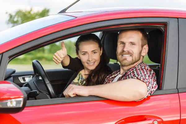 Dos jóvenes sonriendo en un coche rojo — Foto de Stock