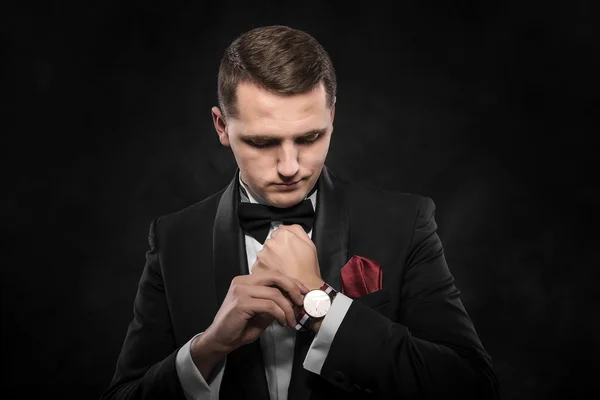 Elegante joven hombre de la moda mirando su reloj  . — Foto de Stock
