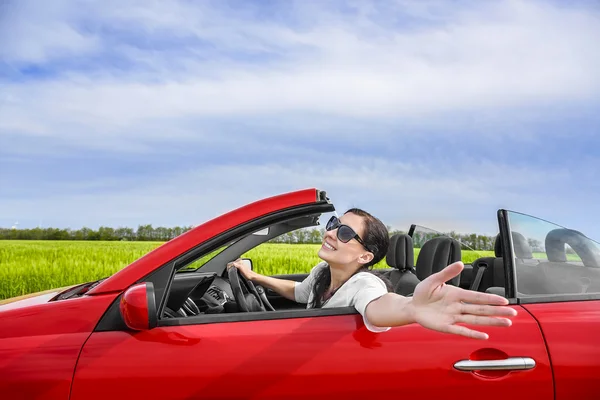 Mulher em um carro vermelho um campo com energia eólica . — Fotografia de Stock