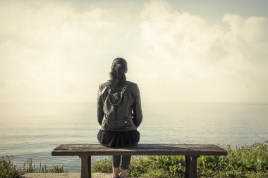 Yalnız kız bankta oturan.