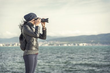 Kız fotoğrafçı fotoğrafları veya videoları denize yakın alır.