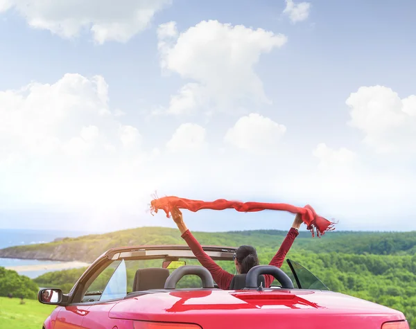 Κορίτσι σε ένα κόκκινο μετατρέψιμο αυτοκίνητο στο παρασκήνιο Θαλασσογραφία. — Φωτογραφία Αρχείου