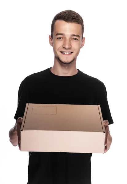 Smiling young delivery man holding and carrying a cardbox isolated on white background — Stock Photo, Image