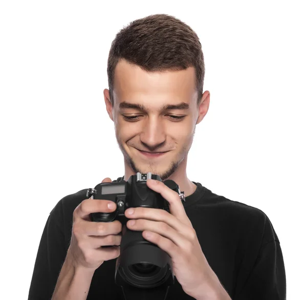 Beau jeune homme tenant un appareil photo reflex numérique . — Photo