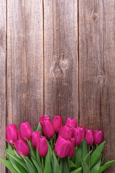 A bouquet of pink tulips on a wooden plank table. — Stock Photo, Image