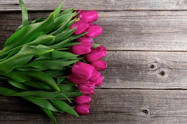 Un ramo de tulipanes rosados sobre una mesa de madera. — Foto de Stock