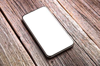 Ahşap bir arka planda beyaz ekranlı akıllı telefon.