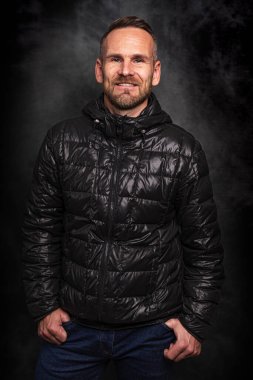 Koyu arkaplanda poz veren yakışıklı bir adam.