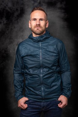 Koyu arkaplanda poz veren yakışıklı bir adam.