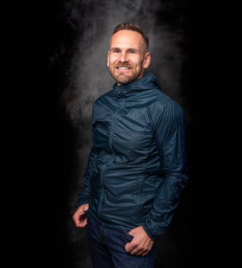 Koyu arkaplanda poz veren yakışıklı bir adam.