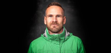 Koyu arkaplanda poz veren yakışıklı bir adam.