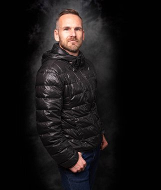 Koyu arkaplanda poz veren yakışıklı bir adam.