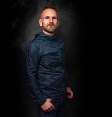 Koyu arkaplanda poz veren yakışıklı bir adam.