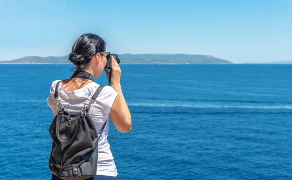 Jonge vrouw fotograaf op een kust op dag. — Stockfoto