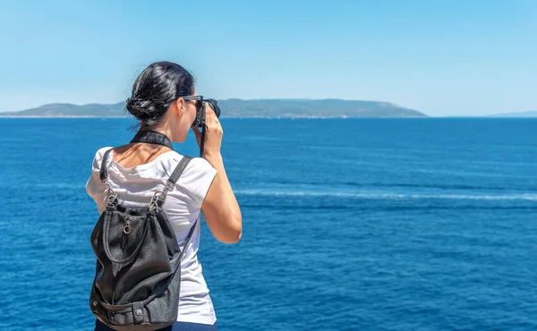 Mladá žena fotograf na pobřeží v den. — Stock fotografie