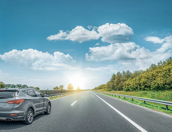 Zwarte auto raast langs de weg tegen de achtergrond van een prachtig landschap. — Stockfoto