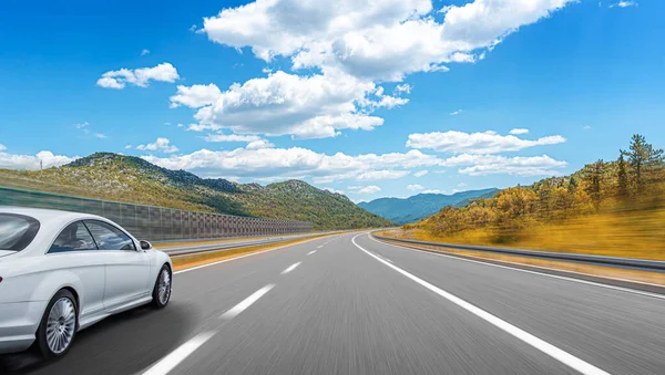 Coche blanco corre a lo largo de la carretera contra el telón de fondo de un hermoso paisaje rural. —  Fotos de Stock