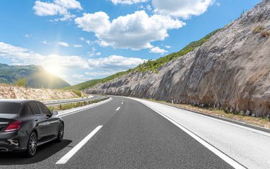 Siyah araba, güzel bir kırsal alanın arka planına doğru hızla ilerliyor..