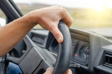 Sürücü ellerini arabanın direksiyonuna koyar..