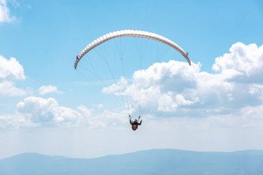 Mavi bulutlu gökyüzüne karşı paraglider.