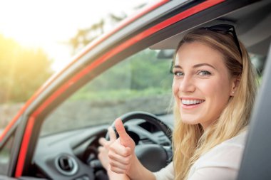 Mutlu güzel kadın kırmızı bir araba kullanıyor..