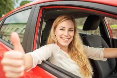 Mutlu güzel kadın kırmızı bir araba kullanıyor..