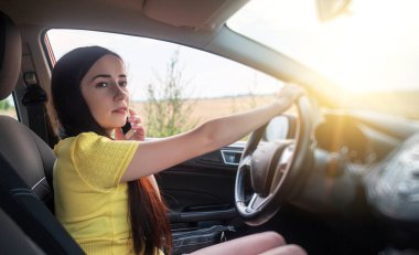 Araba kullanırken telefonla konuşan bir kadın..