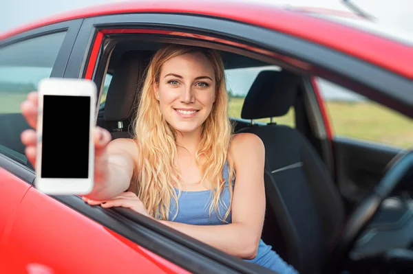 Mujer en coche muestra smartphone con pantalla en blanco. —  Fotos de Stock