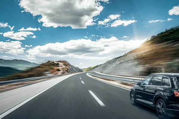 Černé auto se řítí po silnici na pozadí krásné krajiny. — Stock fotografie