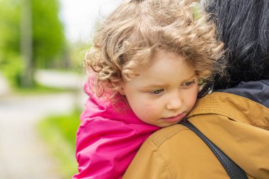 Annesinin kollarında üzgün bir çocuk.