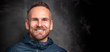 Koyu arkaplanda poz veren yakışıklı bir adam.