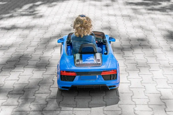 Niño está conduciendo un coche de juguete en el parque. —  Fotos de Stock