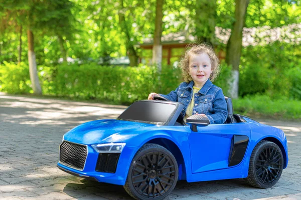 Niño está conduciendo un coche de juguete en el parque. — Foto de Stock