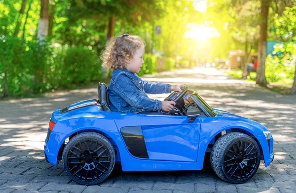 Niño está conduciendo un coche de juguete en el parque. — Foto de Stock