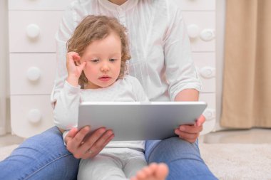 Annesiyle küçük bir kız tablet bilgisayarına bakıyor..