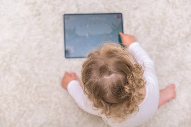 Küçük kız tablet bilgisayarına resim çizer ya da oynar.