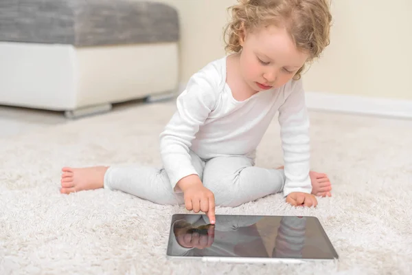 Little girl draws or plays on the tablet computer. — Stock Photo, Image