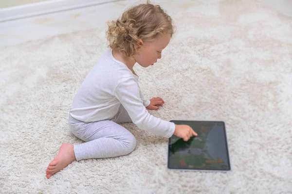 Little girl draws or plays on the tablet computer.