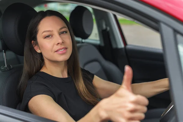 Krásná žena v autě ukazuje palce nahoru. — Stock fotografie