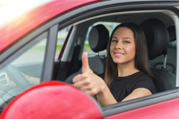 Krásná žena v autě ukazuje palce nahoru. — Stock fotografie