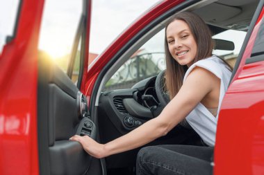 Beautiful young woman opens the car door. clipart