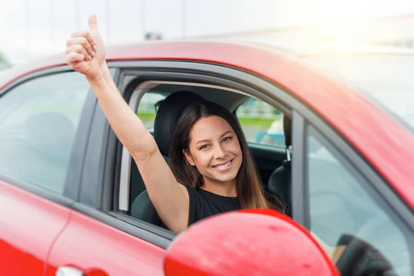 Piękna kobieta w samochodzie pokazuje kciuki do góry. — Zdjęcie stockowe