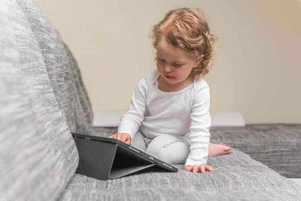 Little girl draws or plays on the tablet computer. — Stock Photo, Image