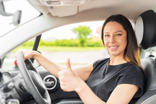 Mulher bonita no carro mostra polegares para cima. — Fotografia de Stock