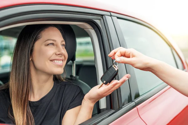 Una mujer atractiva en un coche consigue las llaves del coche. —  Fotos de Stock