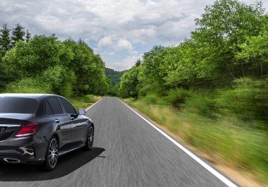 Araba, güneşli bir yaz gününde bir dağ yolunda hareket eder..